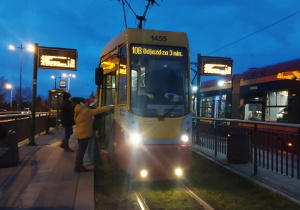 Wolonatriusz stoi przed autobusem i wręcza świąteczną kartkę z życzeniami