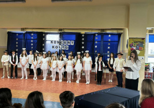 Uczennica - narrator wygłasz swoją rolę. W tle osoby występujące w imprezie.